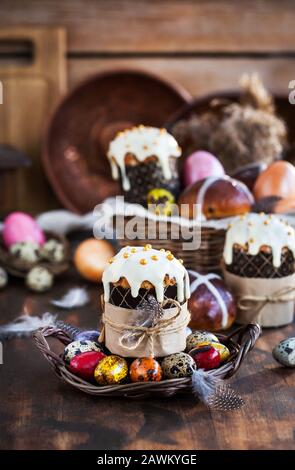 Holiday Easter cakes, hot cross buns and colorful painted eggs on rustic background Stock Photo