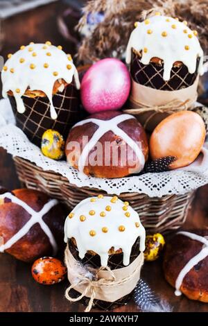 Holiday Easter cakes, hot cross buns and colorful painted eggs on rustic background Stock Photo