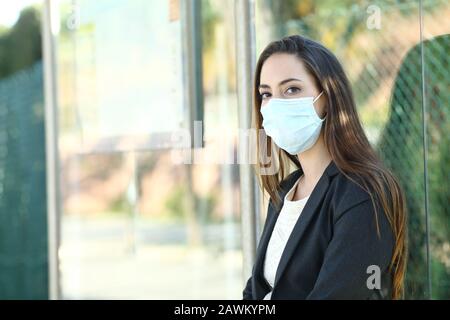 Woman wearing a mask to prevent contagion sitting in a bus stop waiting for transport Stock Photo