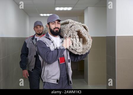 Happy male carrying a carpet in new home Stock Photo