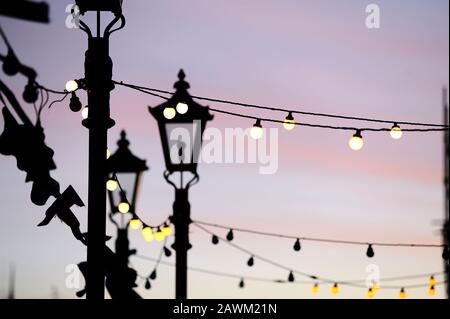 Light bulbs and street lamps at dusk as lights start to come on in St Annes,UK Stock Photo