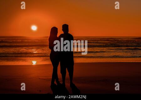 Valentine couple enjoying sunrise on a beautiful beach. Rio Grande do Sul, Brasil. Stock Photo