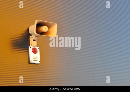 Megaphone for signaling in case of fire on the wall of a warehouse building. Fire safety Stock Photo