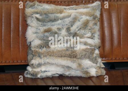 Fur decorative pillow on brown leather sofa background Stock Photo