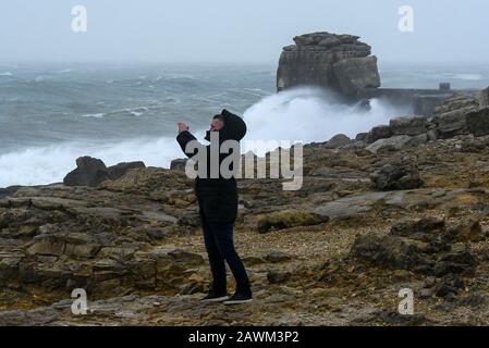 Portland Bill, Dorset, UK.  9th February 2020. UK Weather.  A man at Portland Bill in Dorset photographing the rough seas whipped up by Storm Ciara.  Picture Credit: Graham Hunt/Alamy Live News