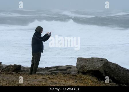 Portland Bill, Dorset, UK.  9th February 2020. UK Weather.  A man at Portland Bill in Dorset photographing the rough seas whipped up by Storm Ciara.  Picture Credit: Graham Hunt/Alamy Live News