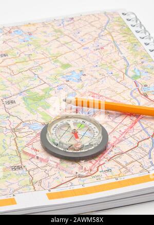 Closeup photograph of a compass on top of a map conveying the concept of travel or adventure. Stock Photo