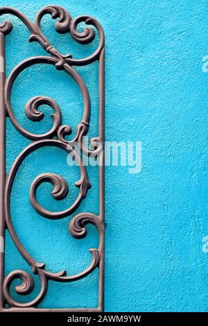 A Decorative Piece of Wrought Iron Mounted to a Bright Colored Stucco Wall Stock Photo