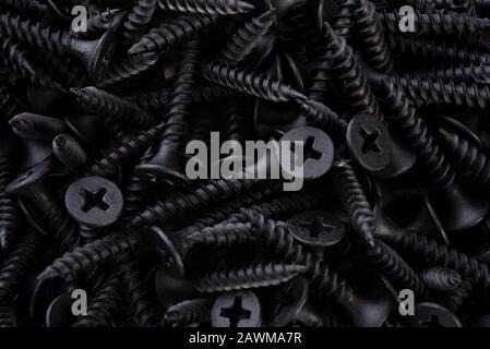 Full frame textured background  - pile of new metal black screws in close-up Stock Photo