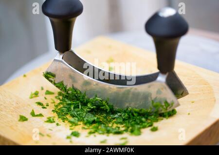 Parsley on a wooden chopping board that has been chopped with a herb cutter. England UK GB Stock Photo