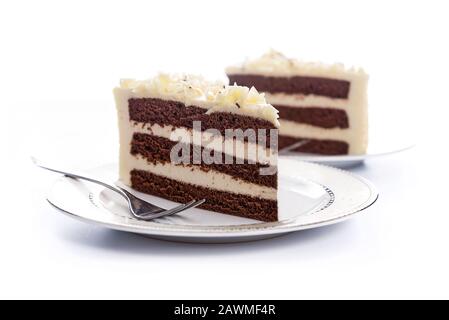 Two  homemade cocoa sponge cakes with sugar mass on a plate with a fork on a white background. Stock Photo