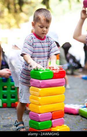 Cute boy playing with buiding toy colorful blocks. Kid with happy face playing with plastic bricks. Plastic Large Toy. Stock Photo