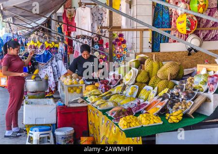 PATTAYA, THAILAND – DEC. 21, 2018: Street vendor selling durians, bananas, mangoes, tangerines, pineapples and tropical fruits on street of Pattaya. Stock Photo