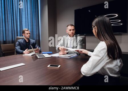 Portrait of three co-workers discussing business plan in office. Stock Photo