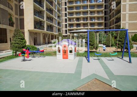 Entertainment area.kids playhouse in the entertainment center. Plastic children play house . Childs swing in a park .Plastic and Empty blue and green Stock Photo