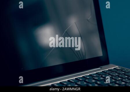 The screen laptop cracked and damaged. A silver laptop with a broken tablet with a cracked display. A close-up picture of part of broken laptop and cr Stock Photo