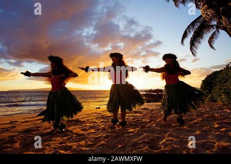 Three hula dancers at sunset at White Rock, Palauea, Maui, Hawaii. Stock Photo