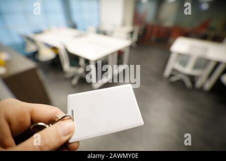 Shallow depth of field (selective focus) image with the hand of a man holding an access card inside an office building. Stock Photo
