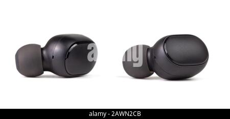 two black wireless bluetooth earbuds isolated on white background - close-up with selective focus. Stock Photo