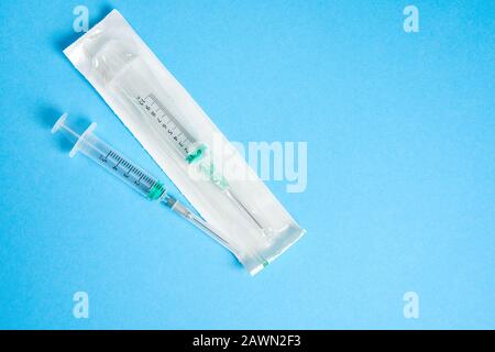 Two plastic disposable medical syringes open and package lie on blue background. Pharmaceutical Concept Health care and medicine. free Copy space Stock Photo