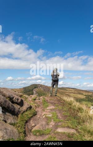 Male hiker at the summit of Hen Cloud looking towards The Roaches, Peak District National Park, Staffordshire, United Kingdom Stock Photo