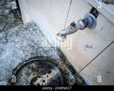Weathered rusty faucet on a concrete wall during daytime Stock Photo