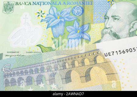 A close up image of a one Romanian leu bank note with a blue and green five euro, European bank note in macro