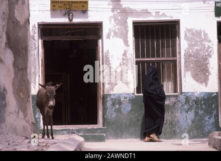 Muslim woman walking by shop in old town of Lamu, Indian Ocean coast of Kenya. Lamu was on major trading route centuries ago from Arabia to Zanzibar on coast of East Africa. Stock Photo