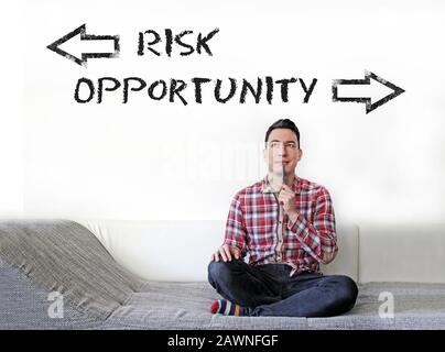 Young man sitting and thinking about choosing between taking risks and opportunities Stock Photo