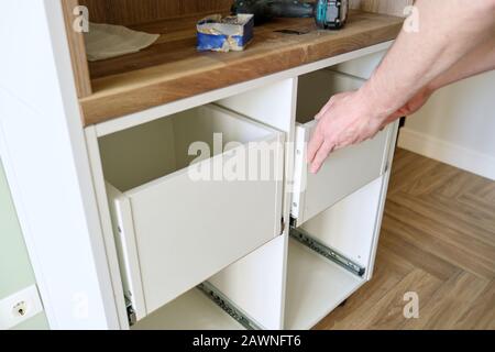 Closeup process of assembling kitchen furniture, hands of male worker Stock Photo