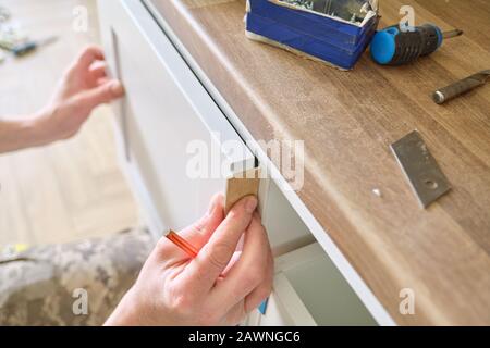 Closeup process of assembling kitchen furniture, hands of male worker Stock Photo