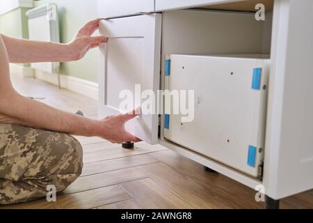 Closeup process of assembling kitchen furniture, hands of male worker Stock Photo