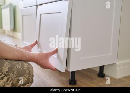 Closeup process of assembling kitchen furniture, hands of male worker Stock Photo