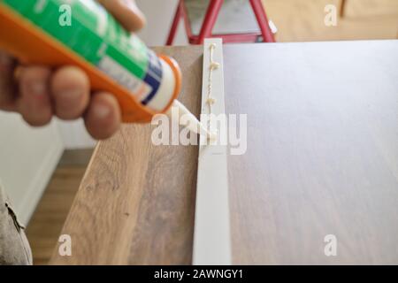 Carpenter male using construction glue when working with wooden board Stock Photo