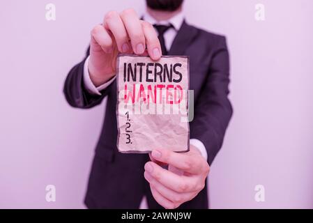 Text sign showing Interns Wanted. Business photo showcasing temporary position with an emphasis on the job training Male human wear formal work suit o Stock Photo