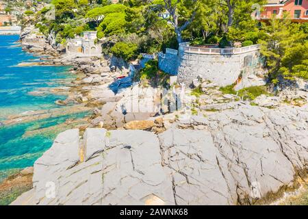 Aerial view on the city with colorful houses located on the rocky coast of ligurian sea, Camogli near Genoa, Italy. Rocky Coastline is washed by Stock Photo