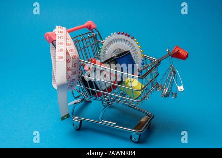 sewing accessories in the grocery basket, needles, threads on a blue background Stock Photo
