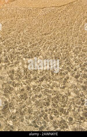 Rocky beach and rippled clear water viewed from above. Abstract natural full frame image. Stock Photo