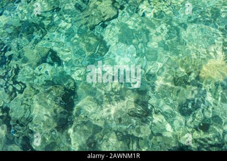 Rippled clear water in light green and turquoise colors and rocky ocean floor, viewed from above. Abstract natural full frame image. Stock Photo