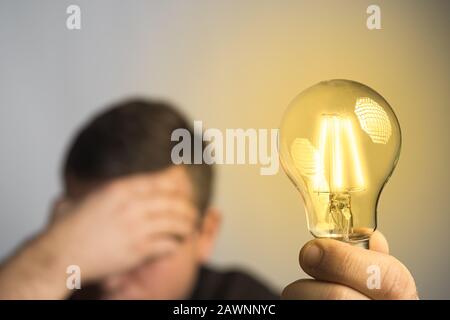 Caucasian man holding glowing incandescent light bulb. Idea or thought abstract concept. Stock Photo