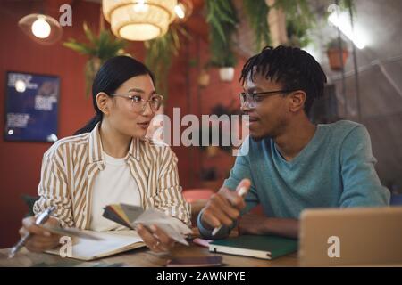 Portrait of two contemporary students working on project together while sitting at table in cafe Stock Photo