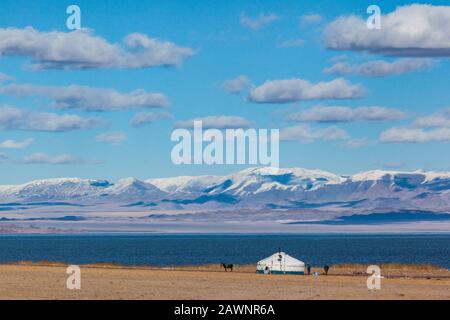 yurt on the shore of Tolbo nuur lake Mongolia clouds snowcapped mountains Stock Photo