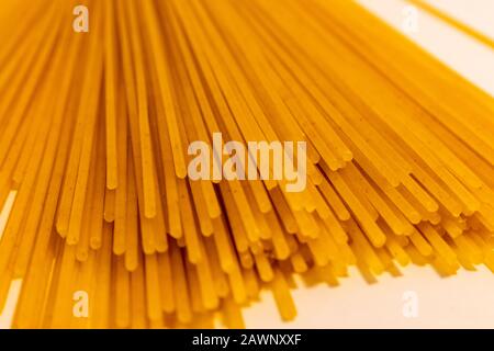 A close-up view of dry spaghettini pasta shows the ends of the dried noodles, with their length extending out of frame. Stock Photo