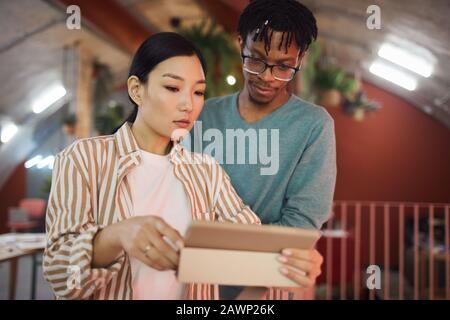 Waist up portrait of Asian young woman using digital tablet while discussing work project with colleague in office, copy space Stock Photo