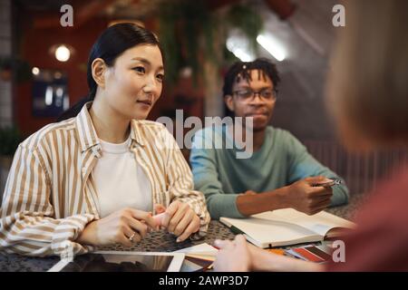 Multi-ethnic group of three business people working on project while sitting at table in cafe, copy space Stock Photo