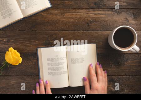 Female hands and opened book, on wooden background. Flat lay, top view, copy space. Stock Photo