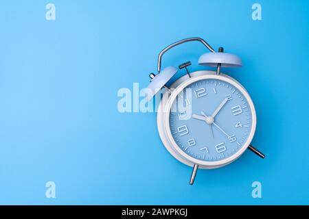 Old fashioned alarm clock on blue background Stock Photo