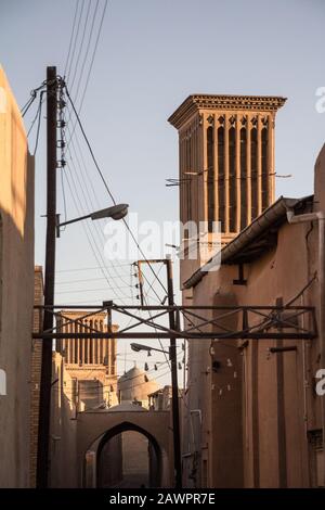 typical Windtower made of clay taken in the streets of Yazd, iran, surrounded by power electrical lines. These towers, aimed at cooling down buildings Stock Photo