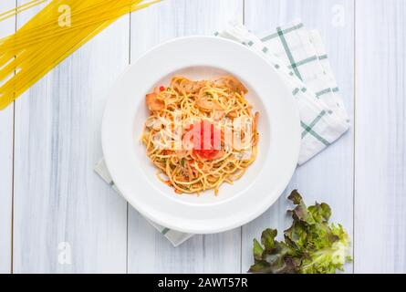 Delicious spaghetti spicy with tobiko with tablecloth on white wood plank table top with raw food material at background. Stock Photo