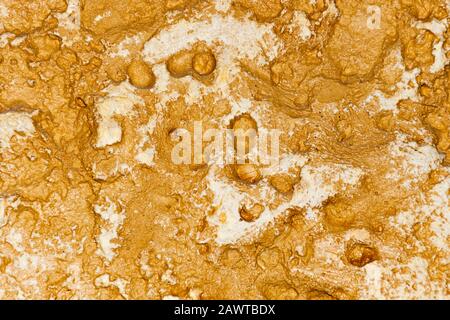A close-up of an uneven stone relief of a yellow wall texture background Stock Photo